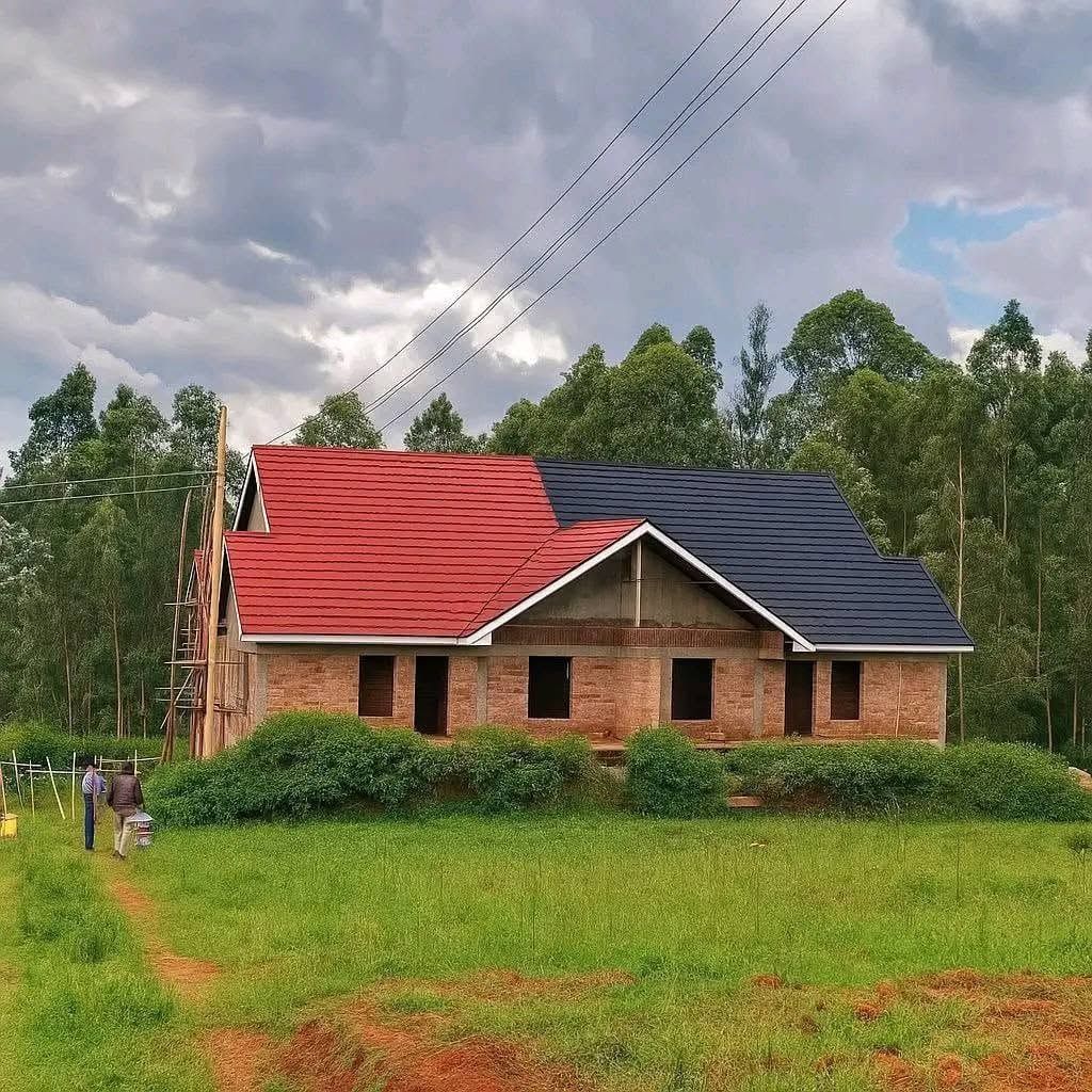 Brick bungalow with a red and grey roof among trees.