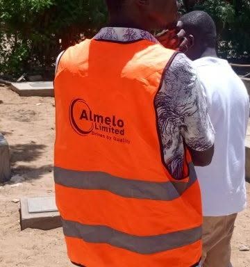 The back of an Almelo engineer’s orange vest, printed "Almelo Limited, Driven by Quality".